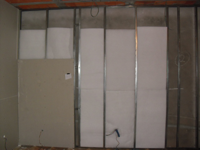 Divisória de Drywall acústica, com estrutura metálica, miolo de Lã de Pet, com uma camada de placa de gesso acartonado, com porta de correr de madeira embutida na parede de drywall.